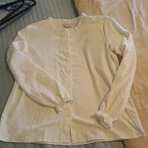 Off-white blouse with polka dot detail and ruffled collar and cuffs